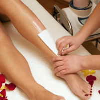 Female getting leg waxing service at beauty salon